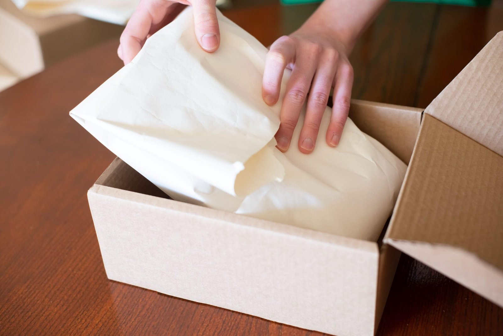 Online seller packing an order into a cardboard box — ecommerce bookkeeping for small businesses